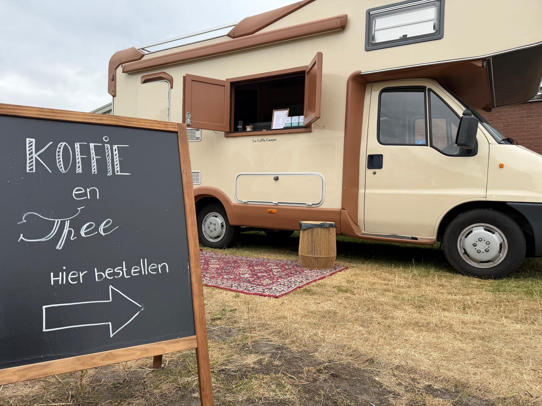 Krijtbord 'Koffie en thee, hier bestellen' naast De Koffie Camper